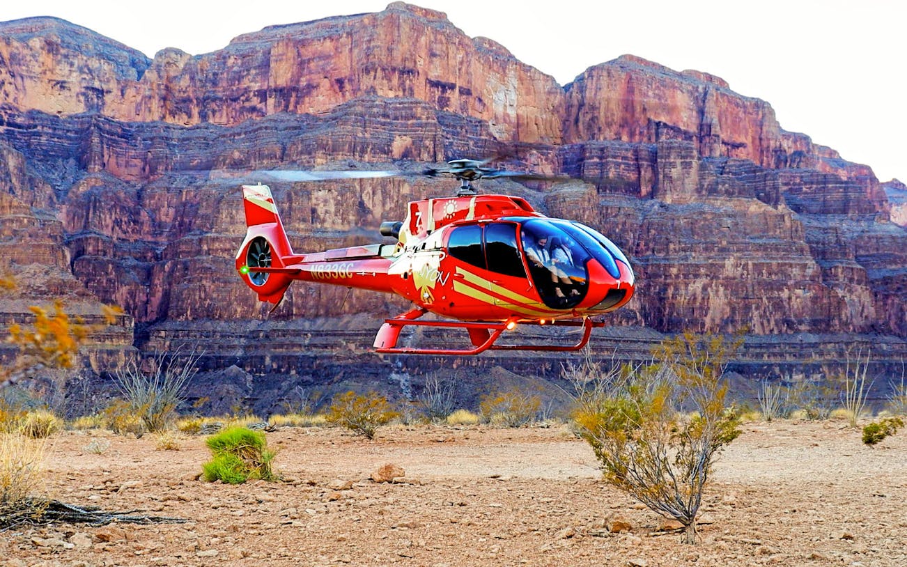 Helicopter landing in the Grand Canyon with rocky cliffs in the background.