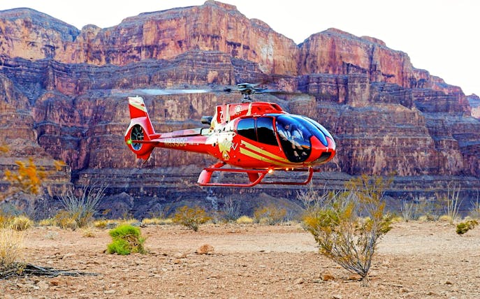 Helicopter landing in the Grand Canyon with rocky cliffs in the background.