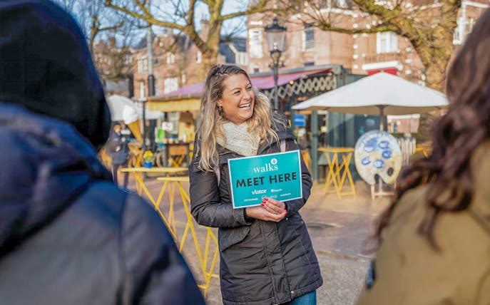 Tour guide holding a "Meet Here" sign for City Canal Cruise, Rijksmuseum & Van Gogh Museum in Amsterdam.