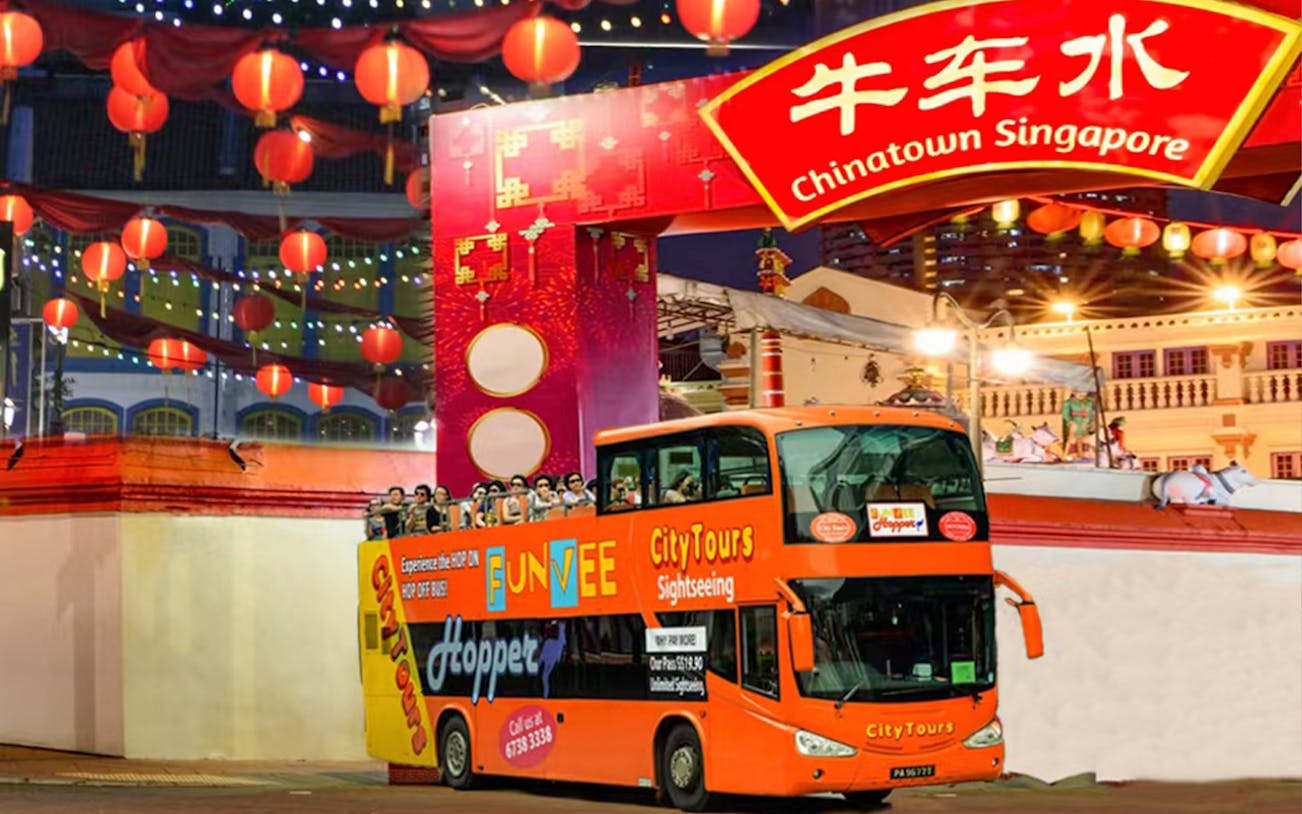 Chinatown Singapore night tour bus under lanterns and archway.