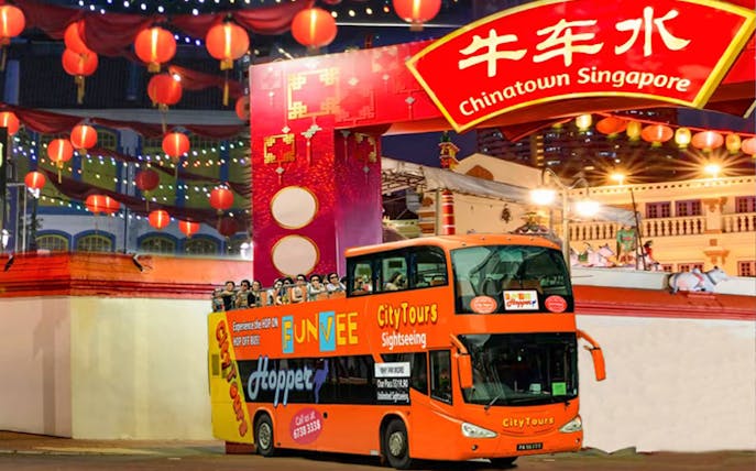 Chinatown Singapore night tour bus under lanterns and archway.