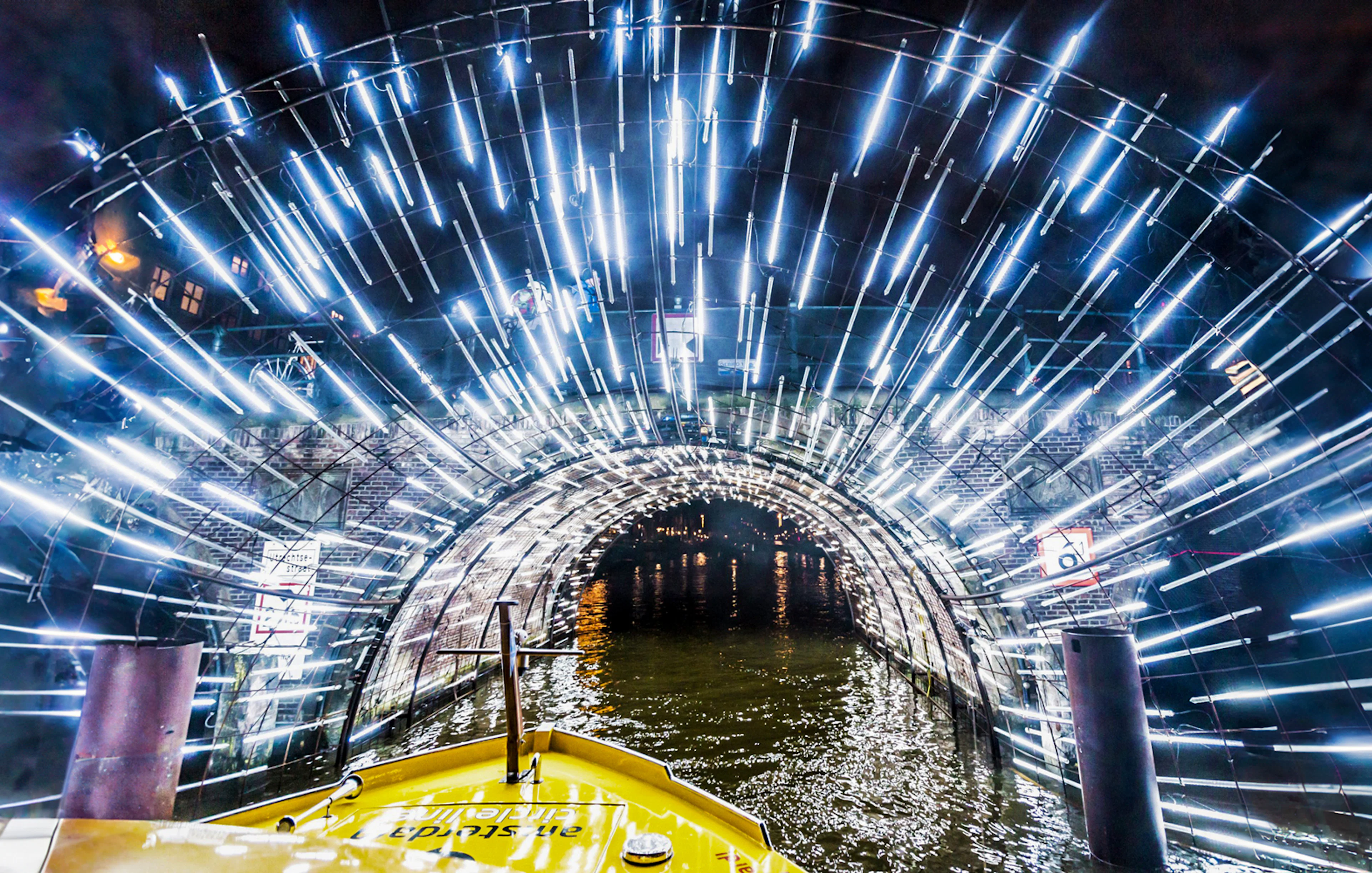 Amsterdam canal cruise passing through illuminated tunnel during Light Festival.