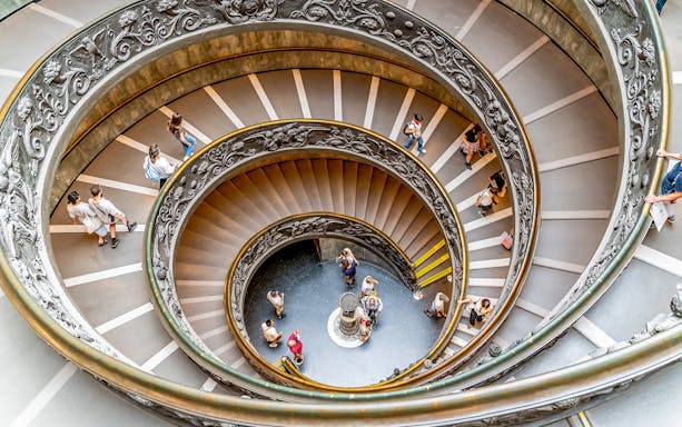 Visitors descending spiral staircase in Vatican City.