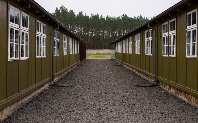 Sachsenhausen Concentration Camp barracks with gravel path and forest background.