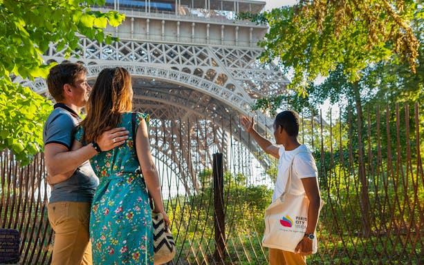 Tour guide showing visitors the Eiffel Tower's 2nd floor during Paris city tour.