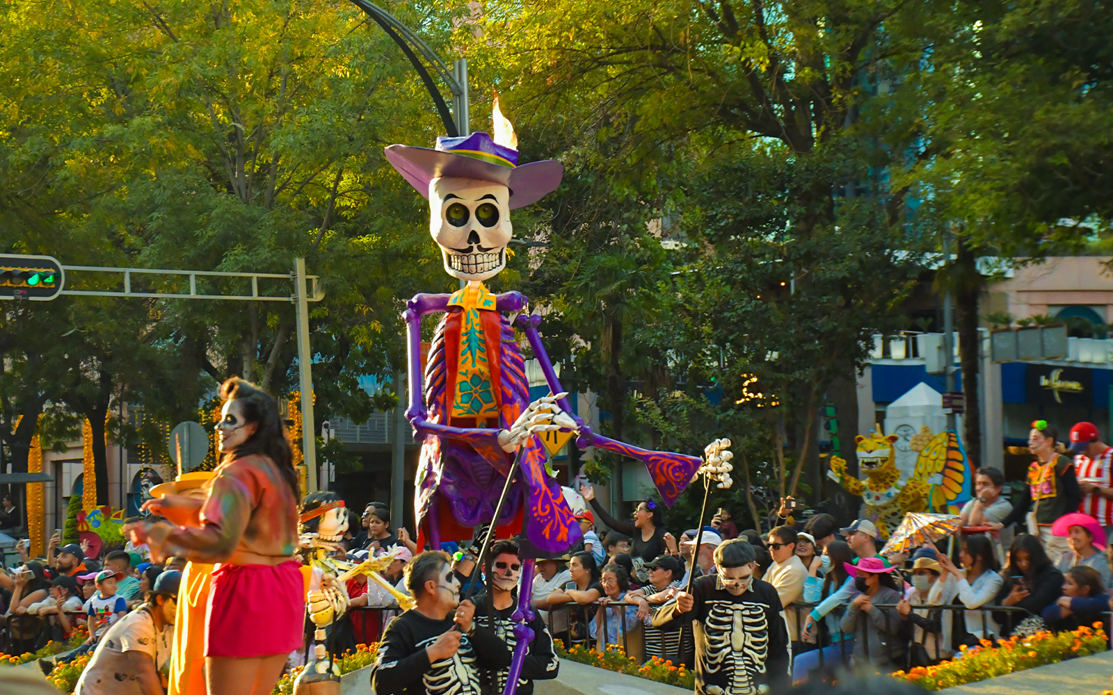 Day of the Dead parade in Mexico with large skeleton figure and costumed participants.