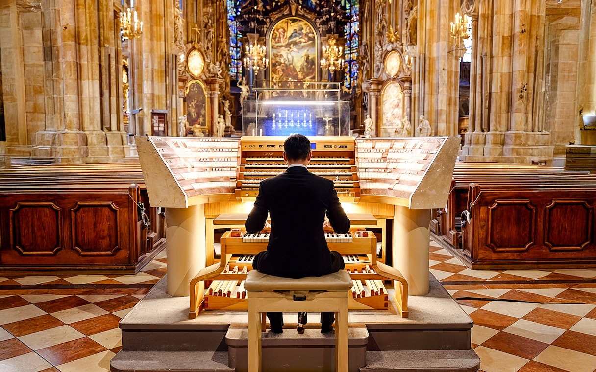 Organist in black tuxedo plays digital organ at St. Stephen’s Cathedral.