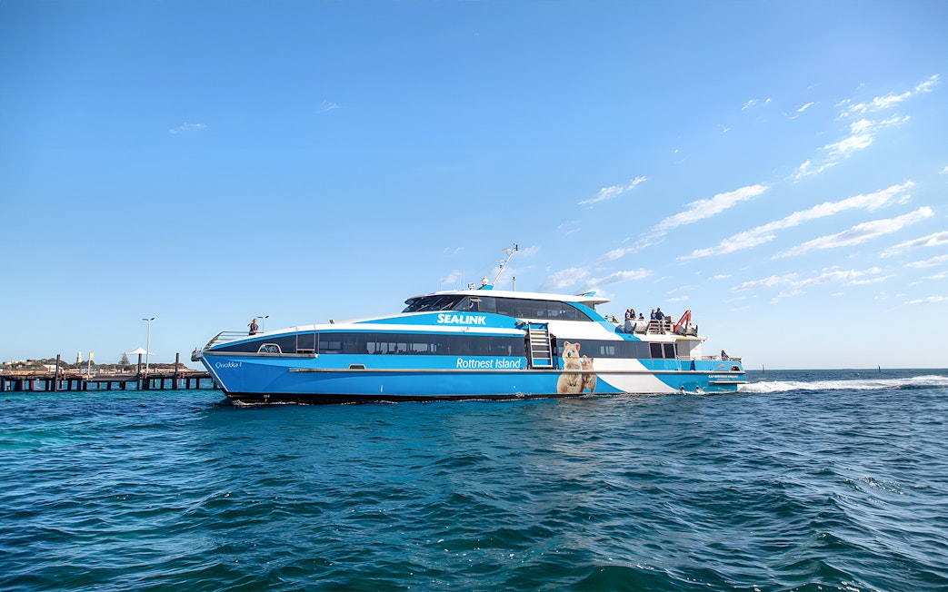 Ferry to Rottnest Island with tourists on deck, coastline visible in background.