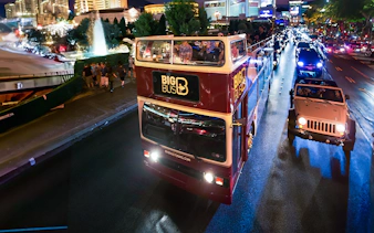 Big Bus night tour on road in Madrid with city lights in background.