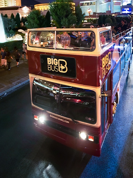 Big Bus night tour on road in Madrid with city lights in background.