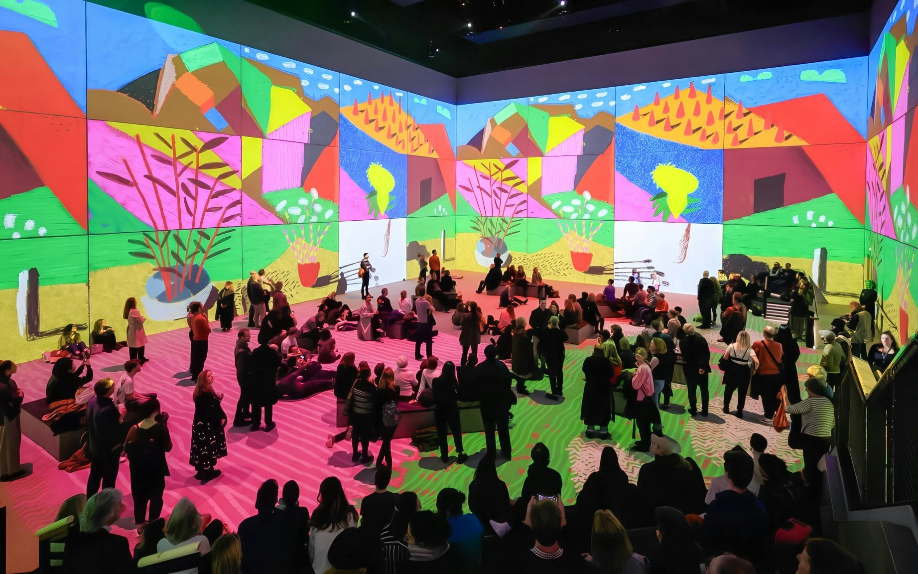 Visitors at David Hockney: Bigger & Closer exhibit viewing vibrant digital art projections.
