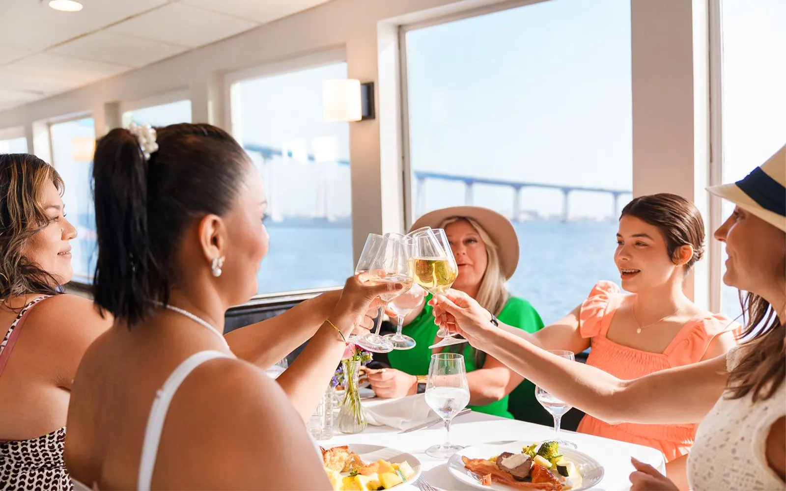 Guests toasting with mimosas on San Diego brunch cruise with bay view.