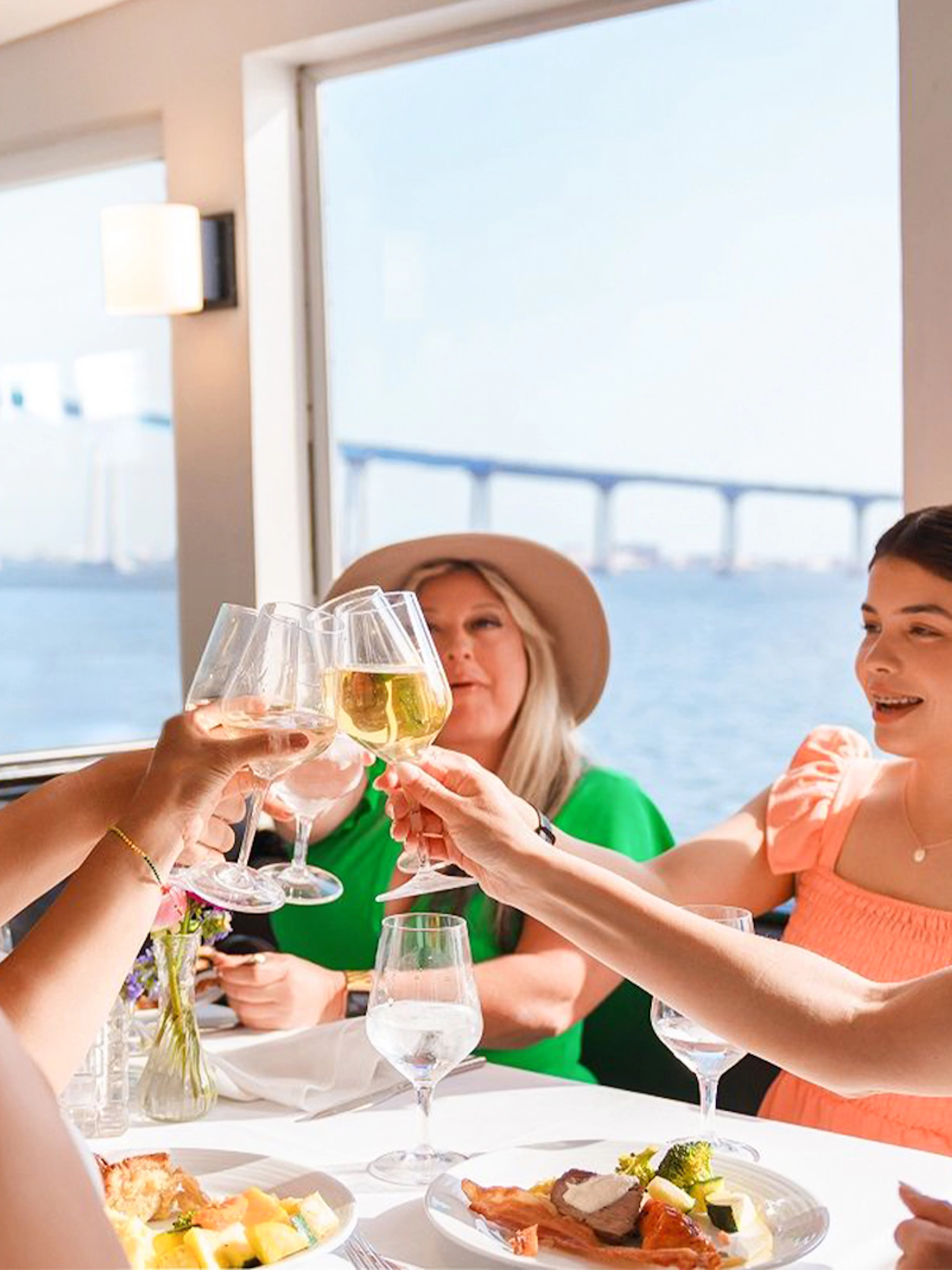 Guests toasting with mimosas on San Diego brunch cruise with bay view.
