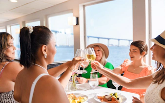 Guests toasting with mimosas on San Diego brunch cruise with bay view.
