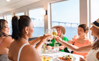 Guests toasting with mimosas on San Diego brunch cruise with bay view.