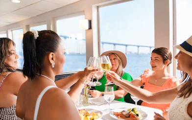 Guests toasting with mimosas on San Diego brunch cruise with bay view.