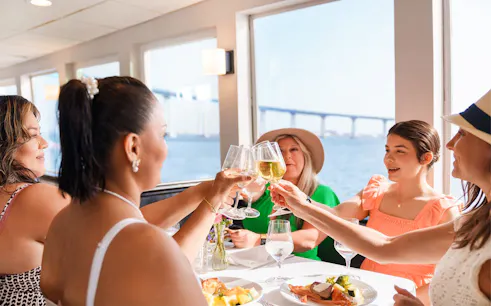 Guests toasting with mimosas on San Diego brunch cruise with bay view.