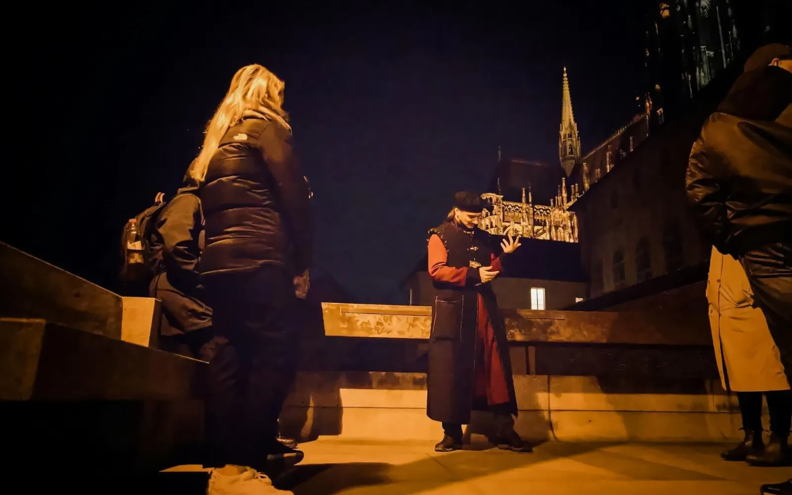 Tour guide in historical attire leading a night tour at Prague Castle.