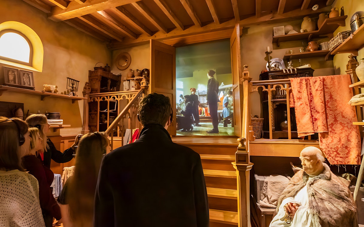 Visitors viewing a historical exhibit at Historium Bruges, featuring a medieval scene projection.