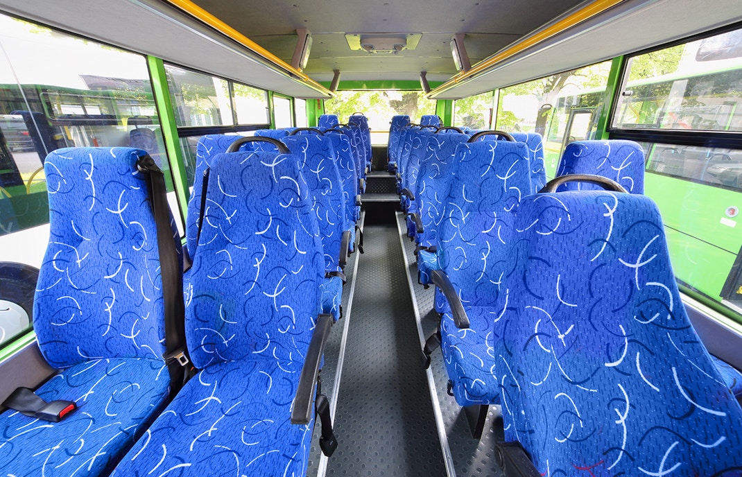 Blue patterned seats inside a tour bus with large windows.