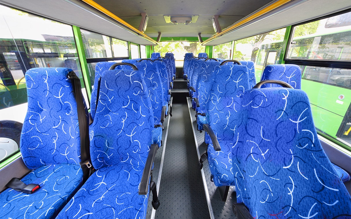Blue patterned seats inside a tour bus with large windows.