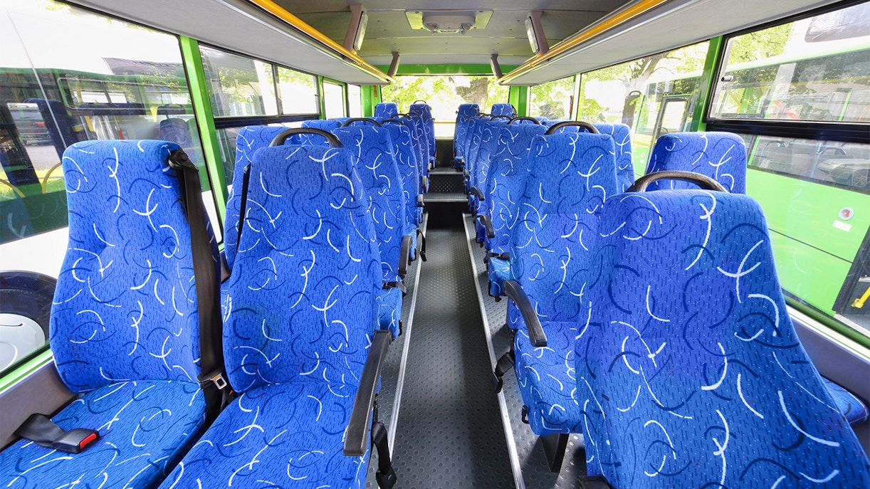 Blue patterned seats inside a tour bus with large windows.