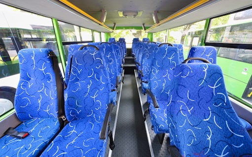 Blue patterned seats inside a tour bus with large windows.
