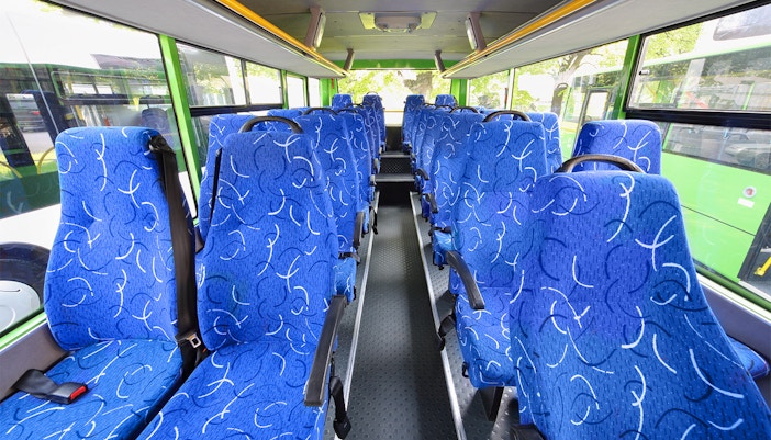 Blue patterned seats inside a tour bus with large windows.