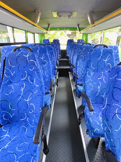 Blue patterned seats inside a tour bus with large windows.