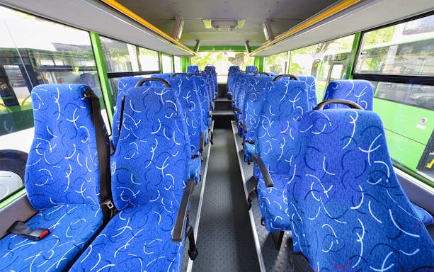 Blue patterned seats inside a tour bus with large windows.