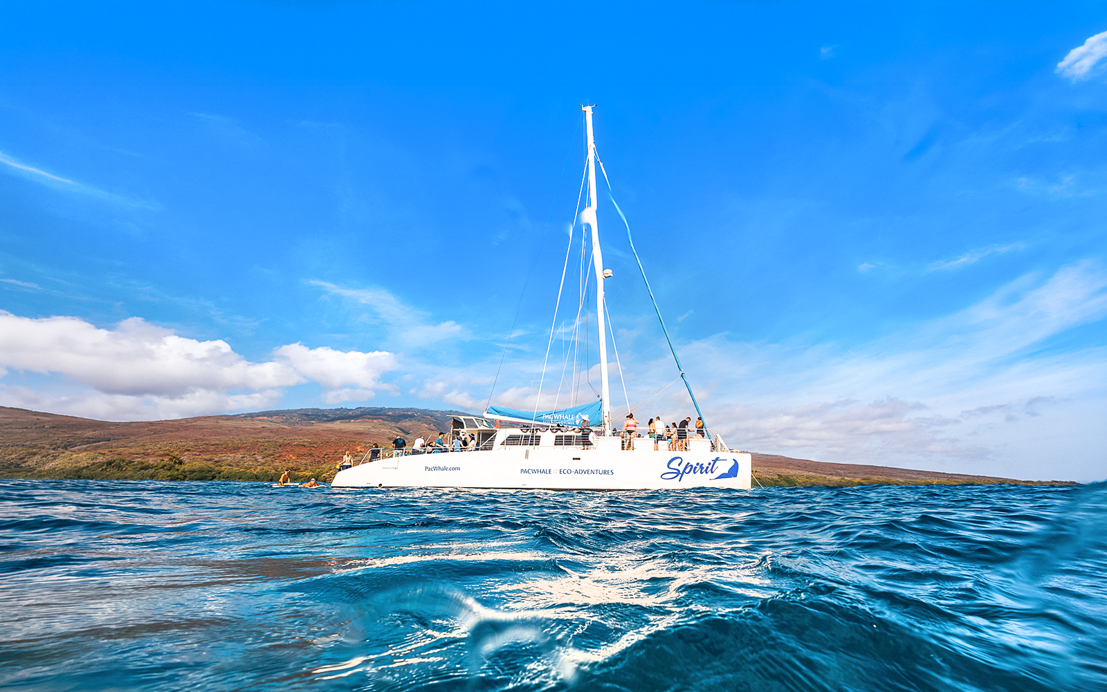 Catamaran on ocean near Lanaʻi, Hawaii, with passengers ready for snorkel and dolphin watch tour.