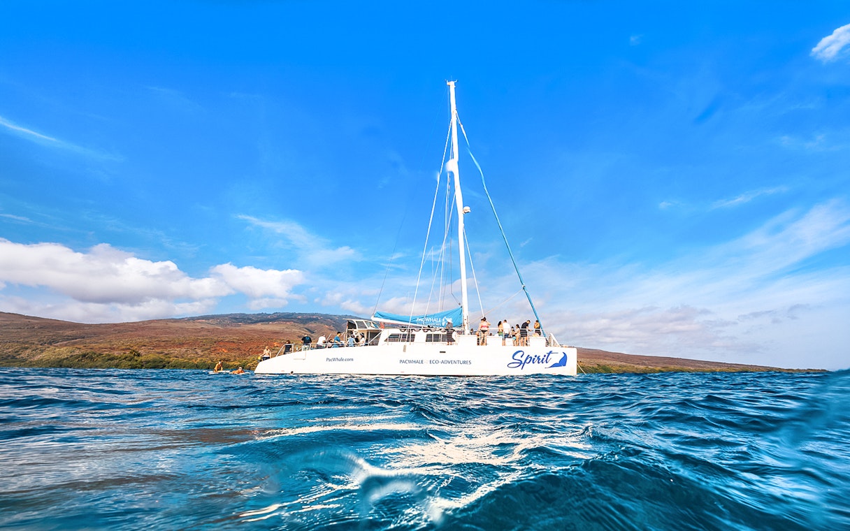Catamaran on ocean near Lanaʻi, Hawaii, with passengers ready for snorkel and dolphin watch tour.