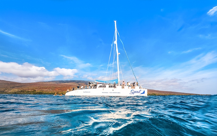 Catamaran on ocean near Lanaʻi, Hawaii, with passengers ready for snorkel and dolphin watch tour.