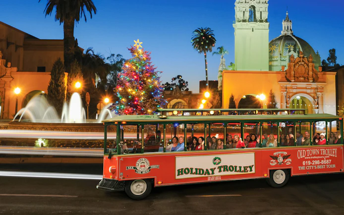 Holiday trolley tour passing festive lights and Christmas tree in San Diego's Old Town.