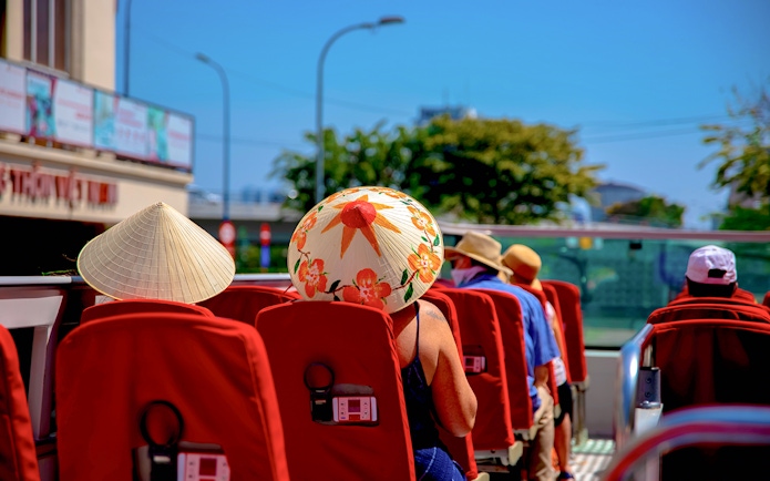 Open-top bus tour in Los Angeles with passengers wearing sun hats.