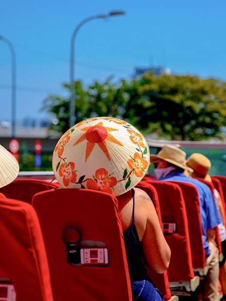 Open-top bus tour in Los Angeles with passengers wearing sun hats.