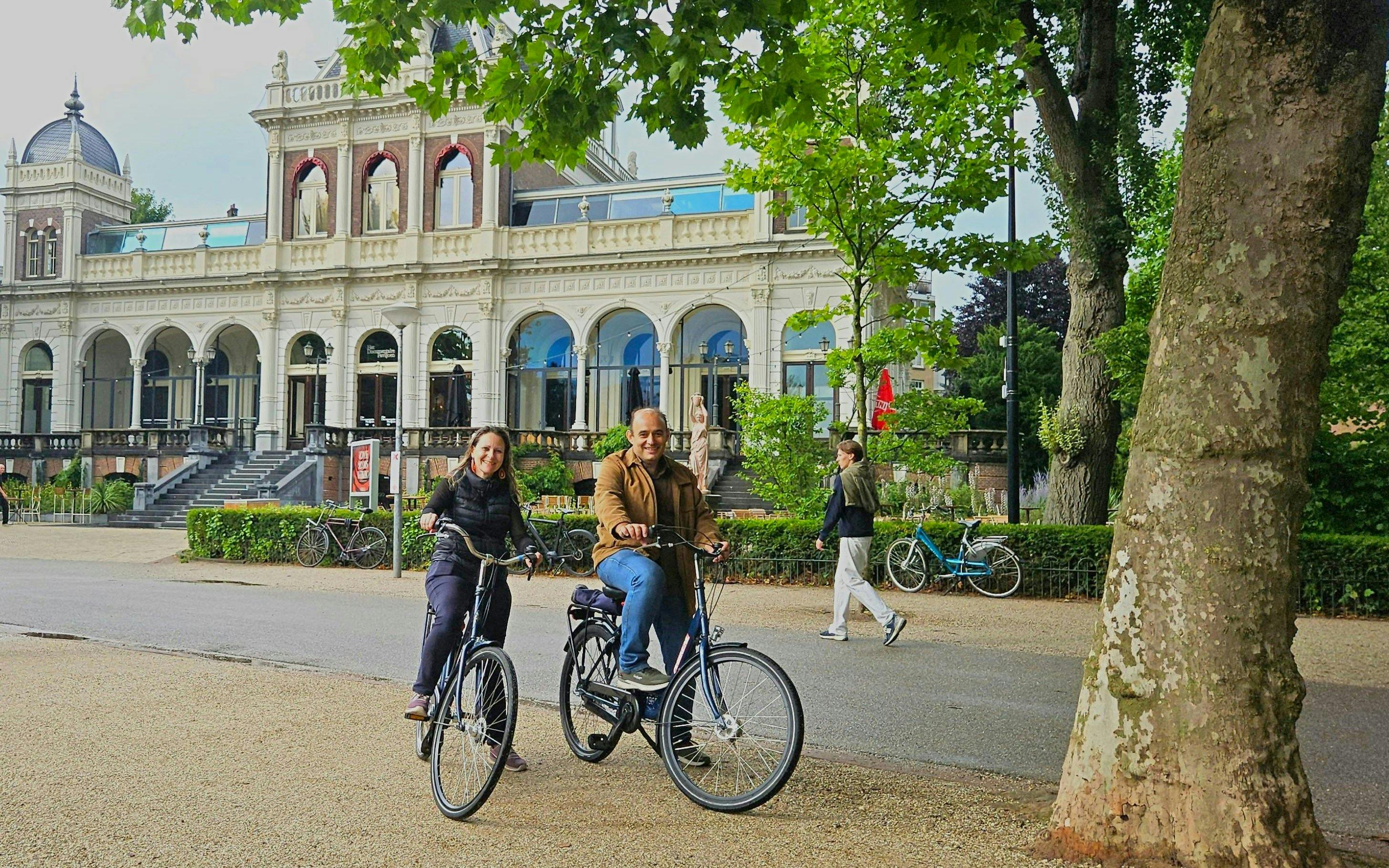 Cyclists enjoying a city highlights bike tour near a historic building.