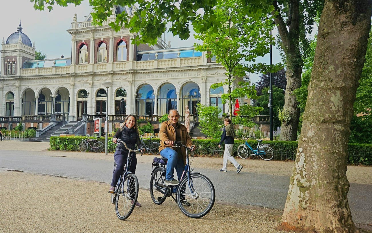Cyclists enjoying a city highlights bike tour near a historic building.