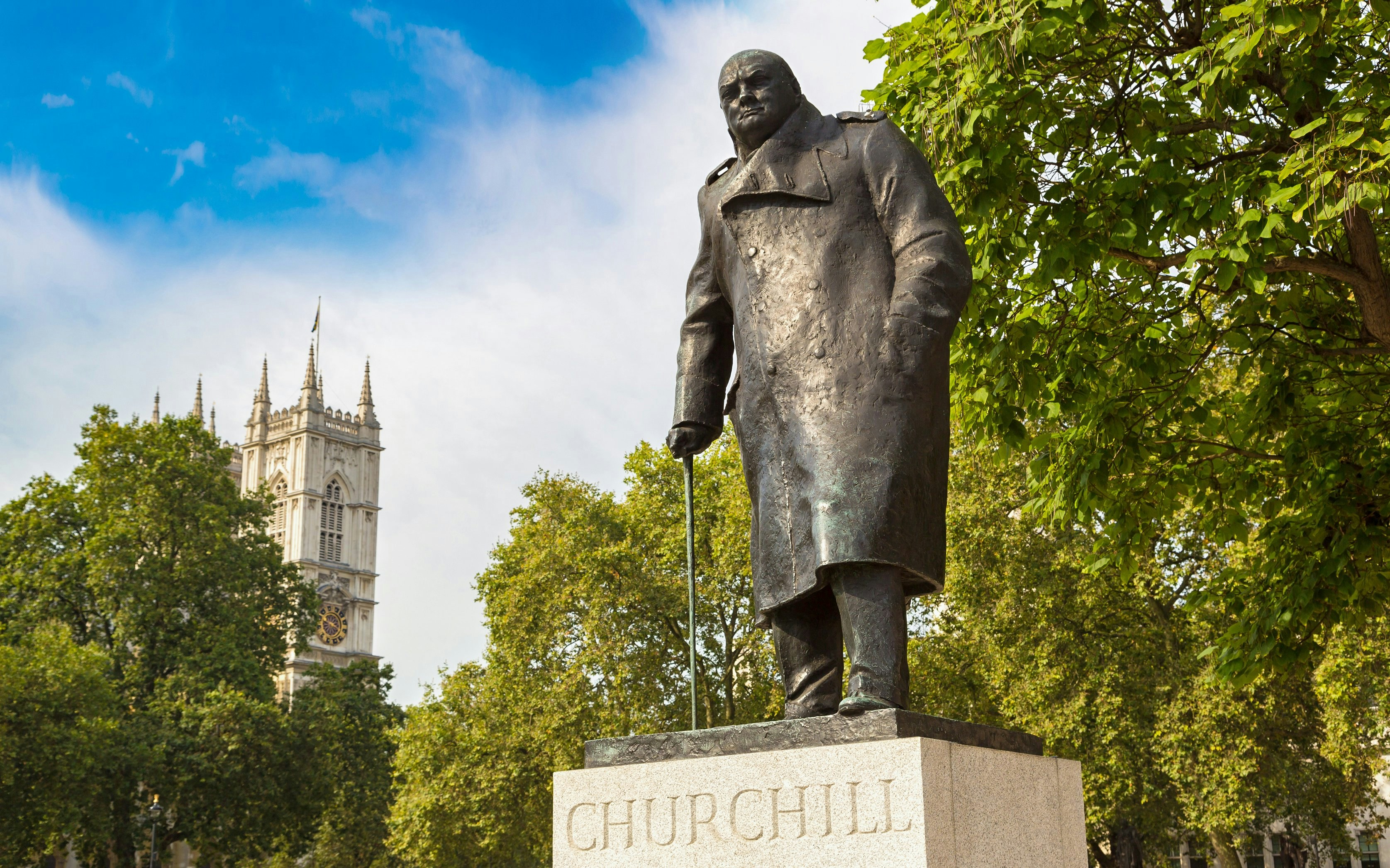 Churchill statue in London with Westminster Abbey in the background.