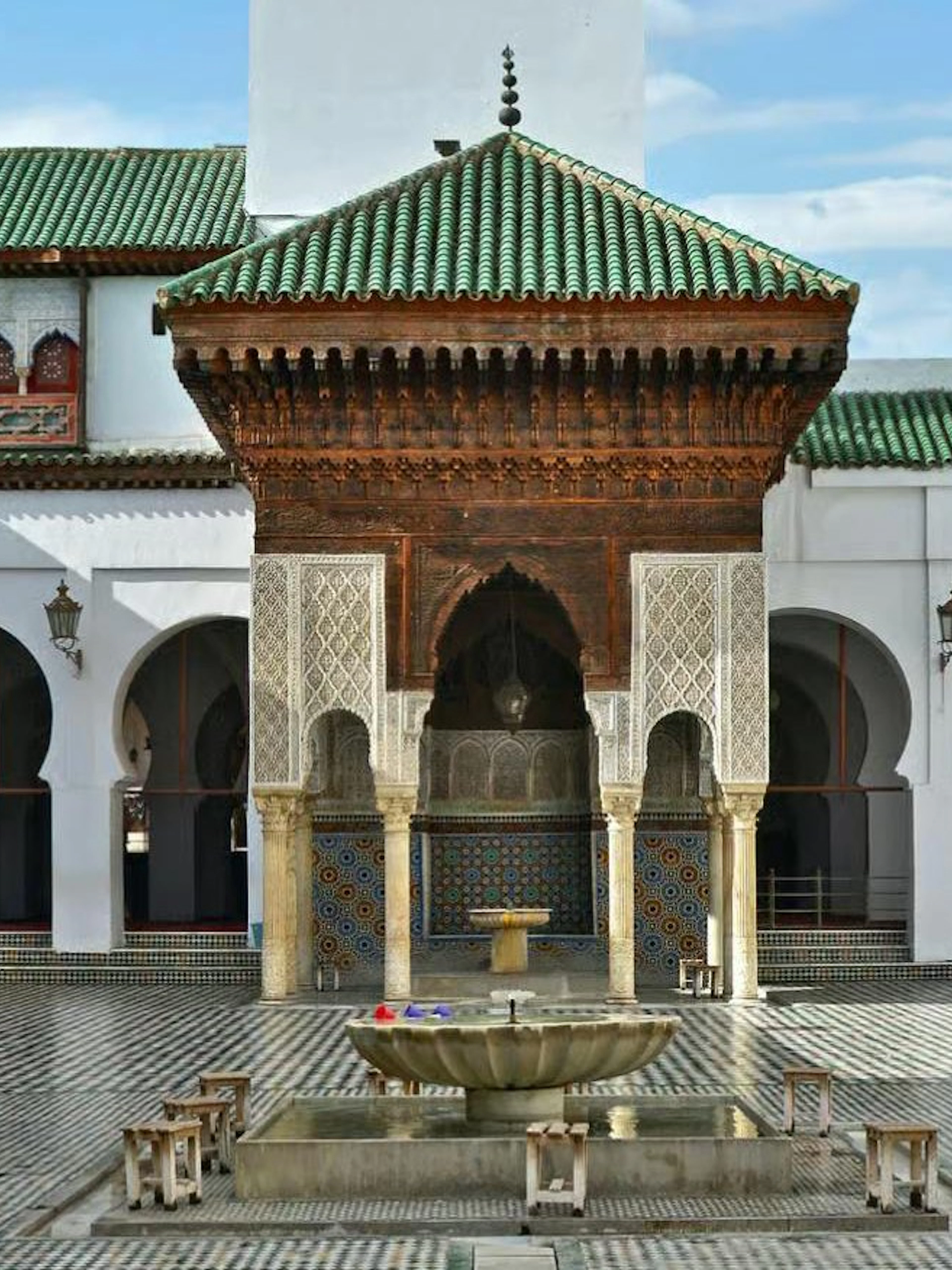 Courtyard of Madrasa in Fes with intricate tilework and central fountain.