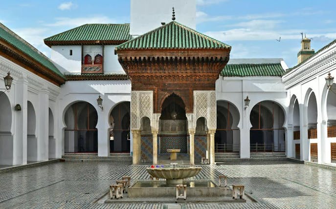 Courtyard of Madrasa in Fes with intricate tilework and central fountain.