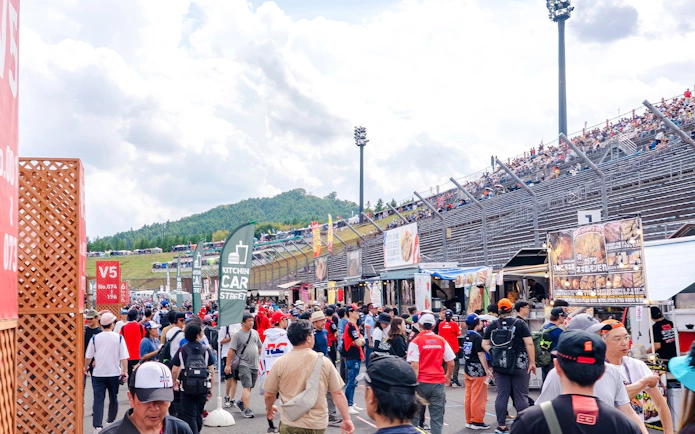 Crowd heading to gallery stands at Motul Grand Prix of Japan 2026, with food stalls nearby.