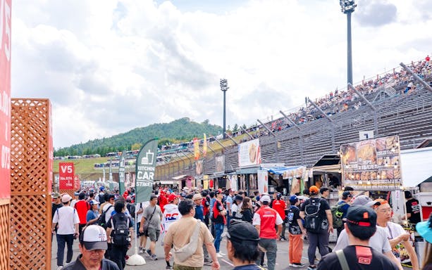 Crowd heading to gallery stands at Motul Grand Prix of Japan 2026, with food stalls nearby.