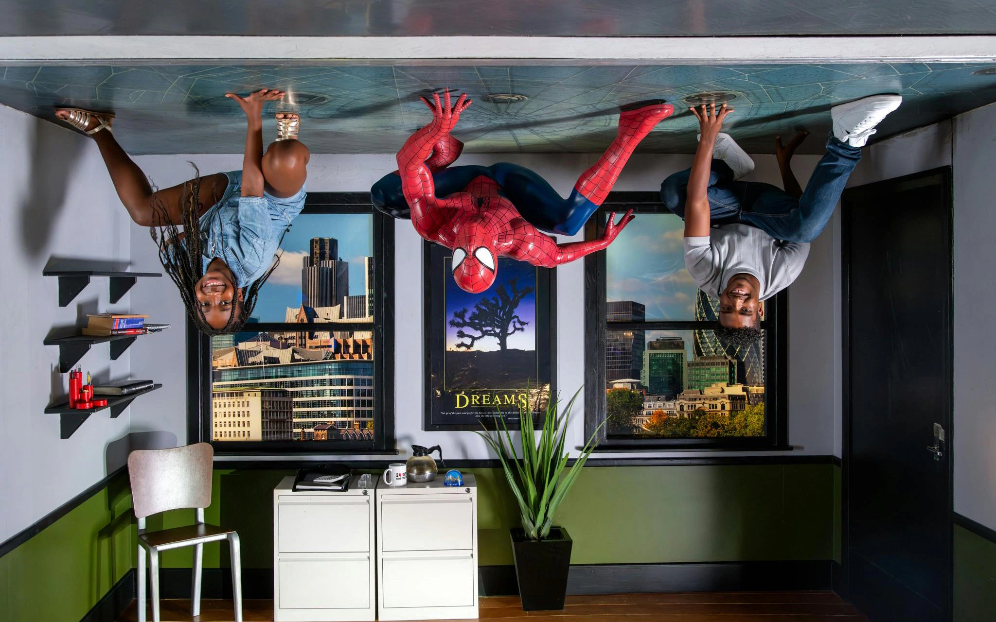 Visitors pose upside down with Spider-Man at Marvel Hall of Heroes exhibit.