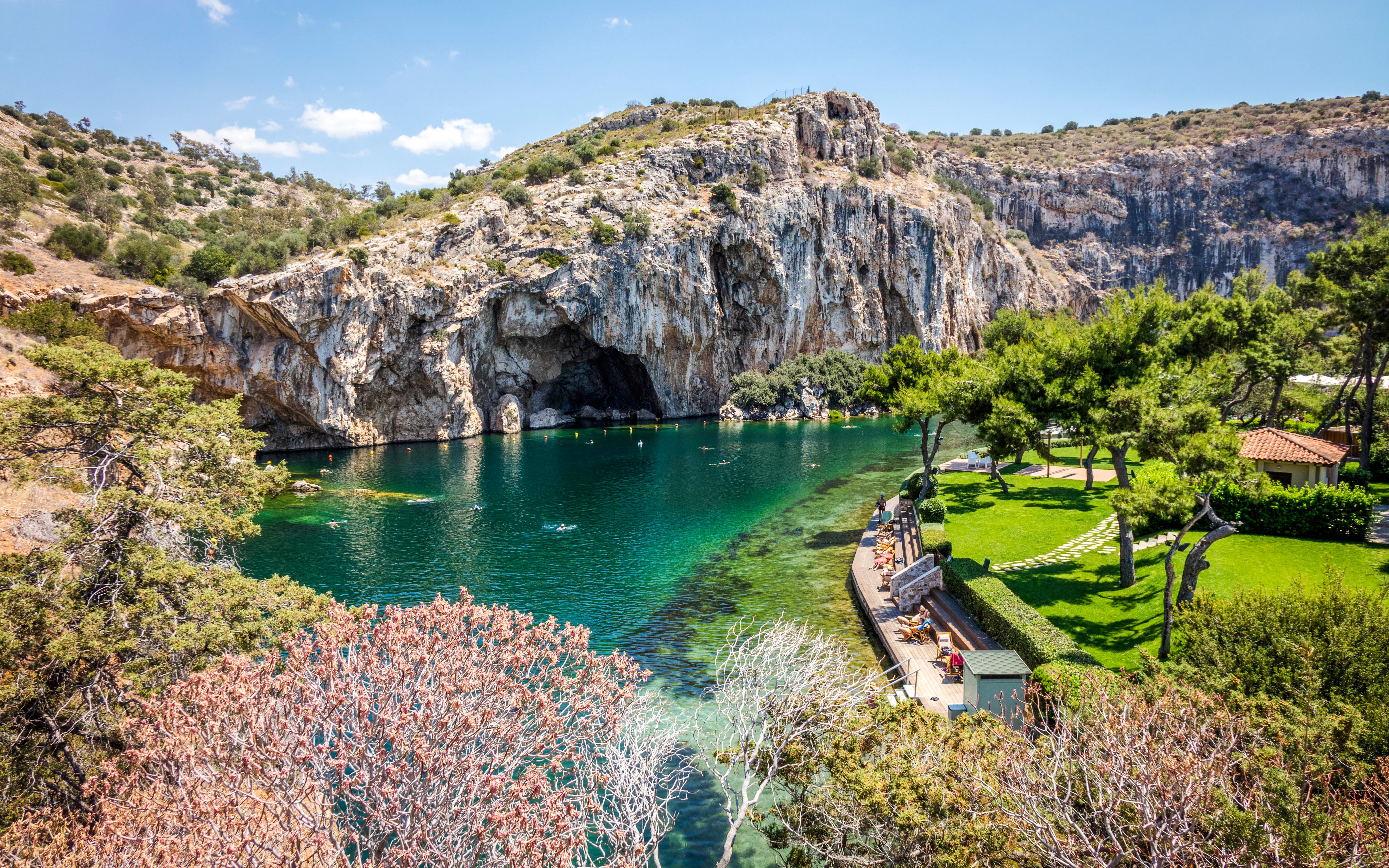 Vouliagmeni Lake in Athens with swimmers and surrounding rocky cliffs.