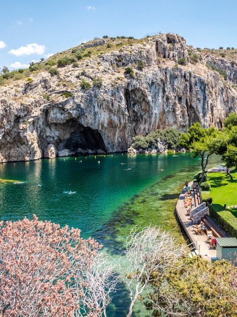 Vouliagmeni Lake in Athens with swimmers and surrounding rocky cliffs.