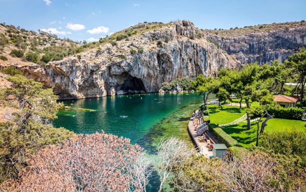 Vouliagmeni Lake in Athens with swimmers and surrounding rocky cliffs.
