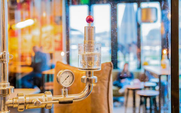 Brewery equipment with pressure gauge in a craft beer tour setting.
