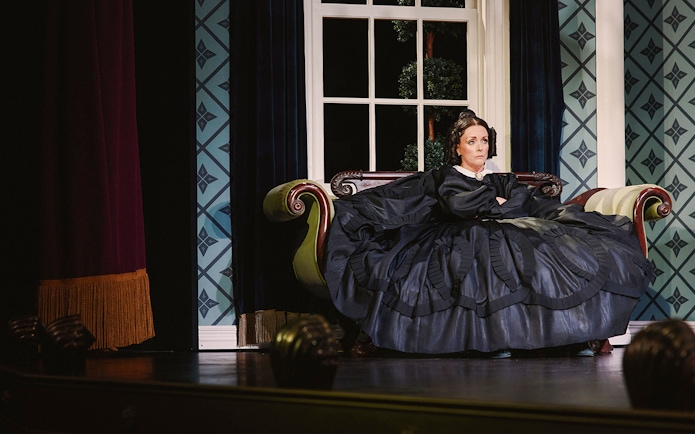 Stage scene from Oh, Mary! Broadway show with actor in period costume on a vintage sofa.