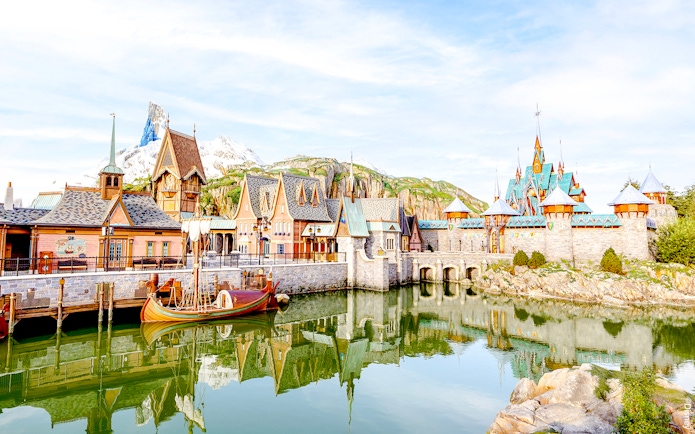 Arendelle village and castle at Disneyland World of Frozen, with a boat on the water.